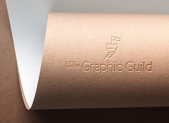 Makroaufnahme des geprägten Logodesign von „The Graphic Guild“ auf einem eingerollten Naturpapier.
