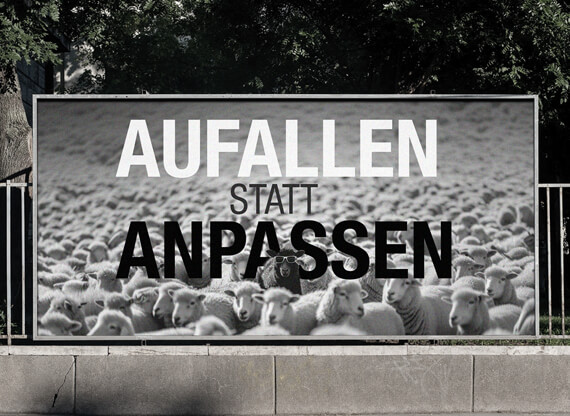 Ein Plakat, welches eine Außenwerbung zeigt, die eine Gruppe von Schafen mit Sonnenbrillen auf einem Plakat zeigt und der Aufschrift: „Auffallen. Anpassen.“