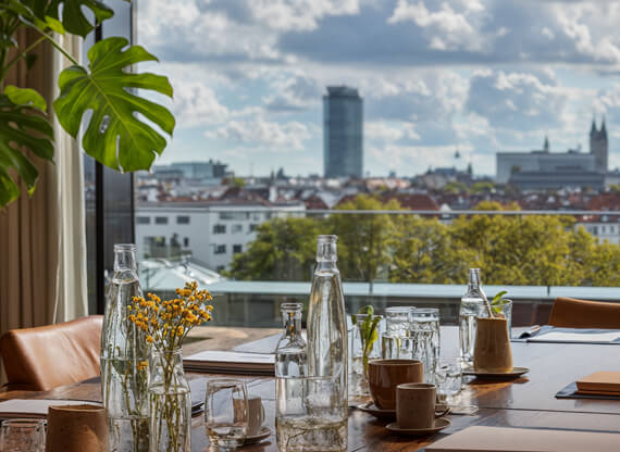 Ein Branding-Workshop hoch oben über den Dächern von München. Ein Besprechungsteschich mit Papierseiten, Stiften und Wassergläsern.