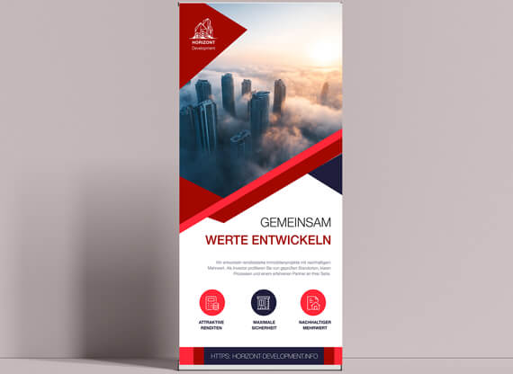 Designkonzepte von Werbematerialien werden anhand eines Rollups präsentiert, das Werbung für einen Immobilienentwickler zeigt, mit Spitzen von Hochhäusern, die geheimnisvoll im Nebel auftauchen und eine moderne, urbane Atmosphäre vermitteln.