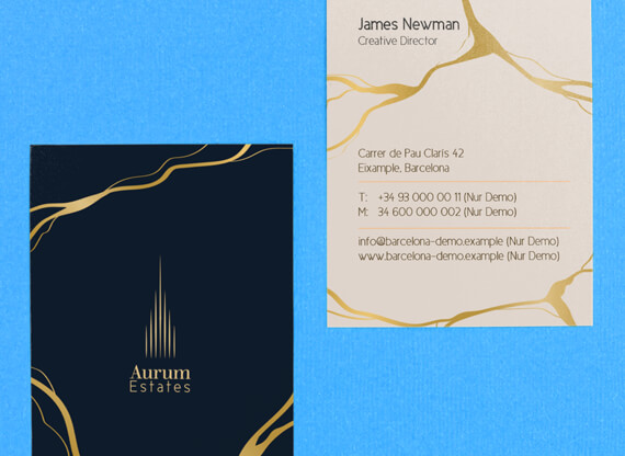 Die Vorder- und Rückseite eines hochwertigen Visitenkartendesigns mit edler Papierstruktur und goldenen Akzenten liegen vor einem satten blauen Hintergrund und strahlen Eleganz sowie hochwertige Handwerkskunst aus.