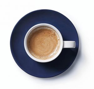 Nahaufnahme einer weissen Espressotasse auf einem blauen Unterteller, von oben fotografiert. Der Espresso sieht lecker und einladend aus.